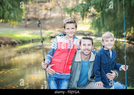 Portrait smiling father and sons with fishing rods Stock Photo