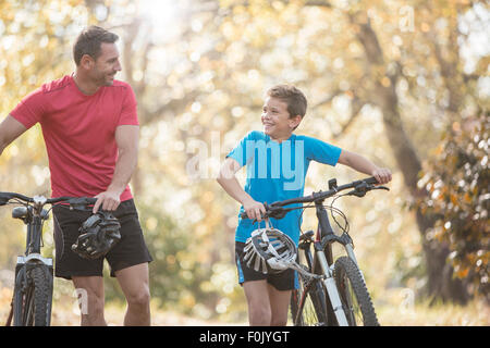 Father and son walking mountain bikes in woods Stock Photo