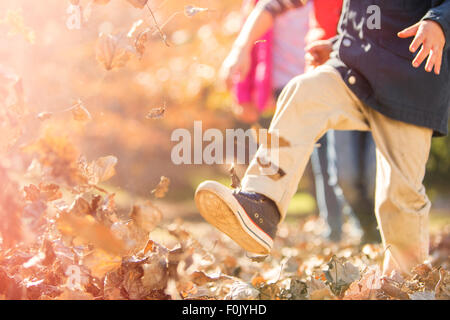 Boy running and jumping in autumn leaves Stock Photo