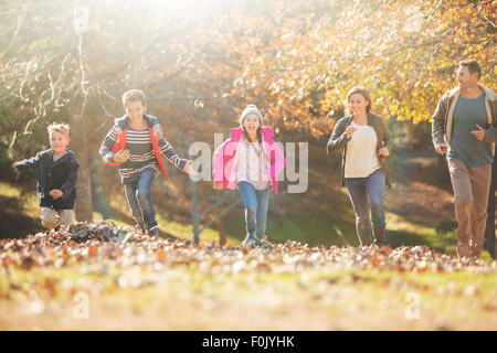 Family running in park with autumn leaves Stock Photo