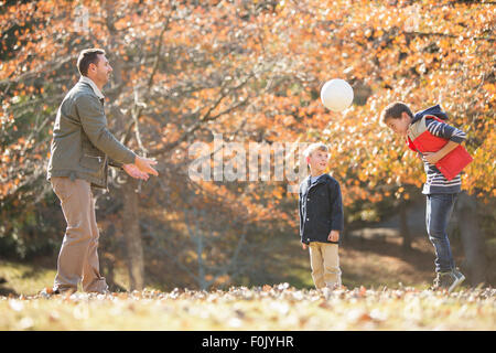 Father and sons playing soccer in autumn park Stock Photo