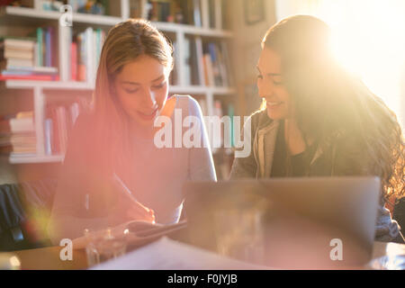 Teenage girls doing homework in sunny room Stock Photo