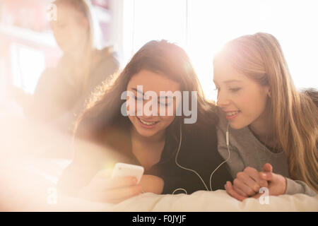 Teenage girls texting with cell phone on bed Stock Photo