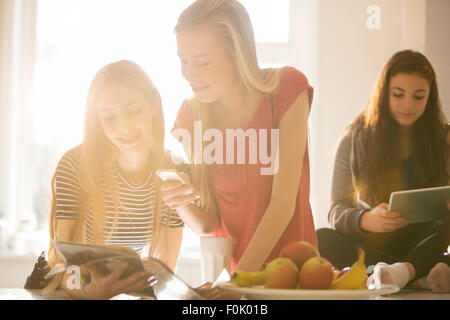 Teenage girls using cell phone and digital tablets Stock Photo