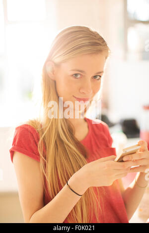 Portrait blonde teenage girl texting with cell phone