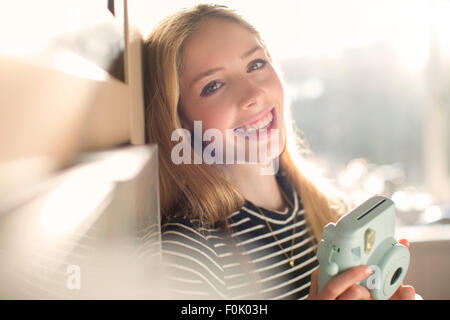 Portrait smiling teenage girl with instant camera