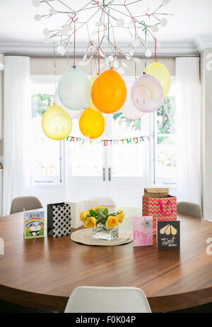 Smiley face balloons and Happy Birthday sign hanging over table with cards Stock Photo