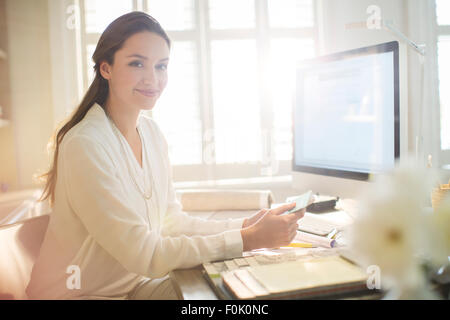 Portrait smiling interior designer with swatches at computer in home office Stock Photo