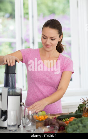 Woman juicing fresh fruits and vegetables Stock Photo