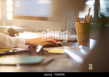 Businesswoman using computer and computer mouse at desk Stock Photo