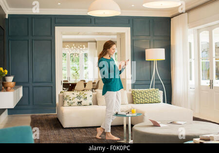 Woman texting with cell phone in home showcase living room Stock Photo