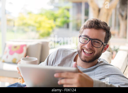 Portrait smiling man drink coffee and using digital tablet Stock Photo