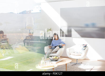 Woman reading magazine in sunny living room Stock Photo