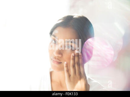 Serious woman applying moisturizer to face Stock Photo