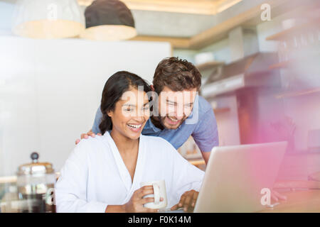 Laughing couple drinking coffee and using laptop Stock Photo