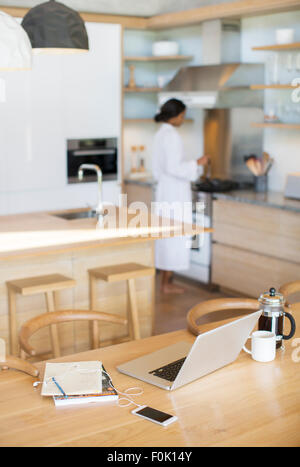 Laptop, French press coffee, cell phone and notebook on kitchen table Stock Photo