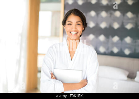 Portrait smiling woman in bathrobe holding digital tablet Stock Photo