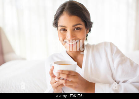 Portrait smiling woman in bathrobe drinking tea Stock Photo
