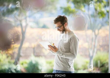 Man drinking orange juice and using digital tablet on patio Stock Photo