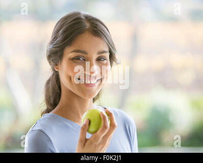 Close up portrait smiling woman eating green apple Stock Photo