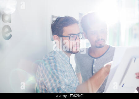 Creative businessmen reviewing paperwork in sunny office Stock Photo