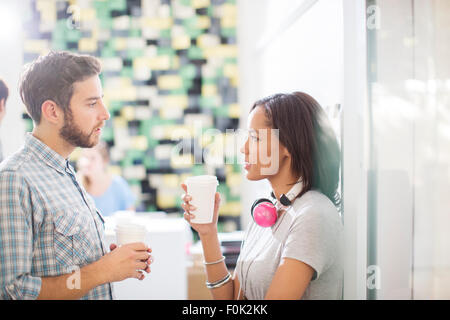 Creative business people with coffee and headphones talking in office Stock Photo