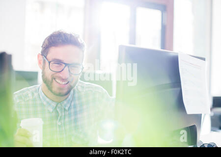 Portrait enthusiastic creative businessman drinking coffee at computer Stock Photo