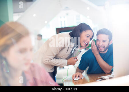 Creative business people sharing and listening to headphones in office Stock Photo