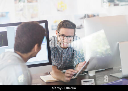 Creative designers talking between computers in office Stock Photo