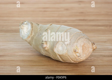 Close-up of a piece of fresh ginger root on a wooden chopping board. Stock Photo