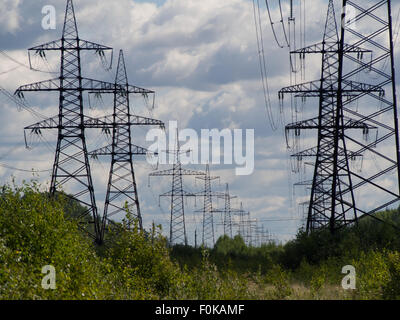 a high voltage power pylons against blue sky and sun rays Stock Photo ...