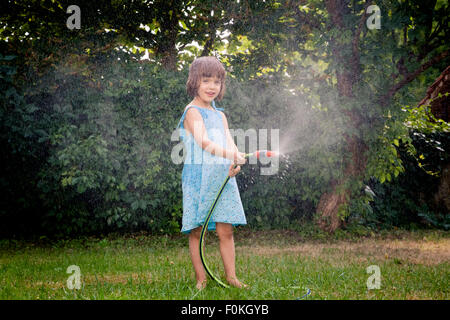 Little girl with garden hose Stock Photo