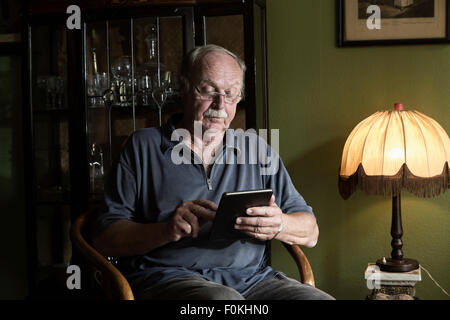 Senior man using mini tablet at home Stock Photo