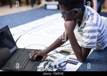 Schoolboy with laptop in robotics class testing vehicle on test track Stock Photo