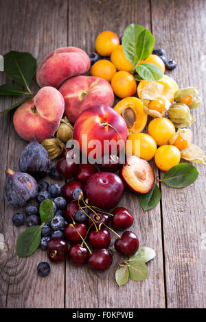 Fresh stone fruits cherries peaches plums on wooden table Stock Photo
