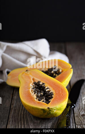 Cut papaya exotic fruit on a wooden table Stock Photo