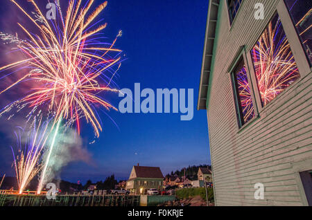 July 4th fireworks explode over a harbor on the Maine coast in celebration of Independence Day. Stock Photo