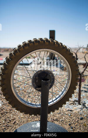 Art installation in the desert of Utah (USA). Motorcycle wheel on a stalk in a cemetery with a blue sky in the background. Stock Photo