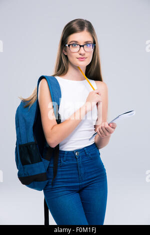 Portrait of a female teenager with backpack holding pencil and notebook isolated on a white background Stock Photo