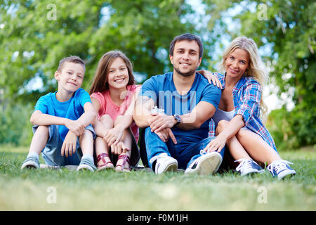 Happy family sitting on lawn Stock Photo