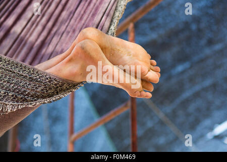 Man relaxing in hammock, lazy vacations. Only the feet are visible from the rest of the body. Stock Photo