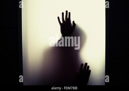 Silhouette of little child holding up hands. Conceptual image of childhood fears, abuse and safety of children. Stock Photo