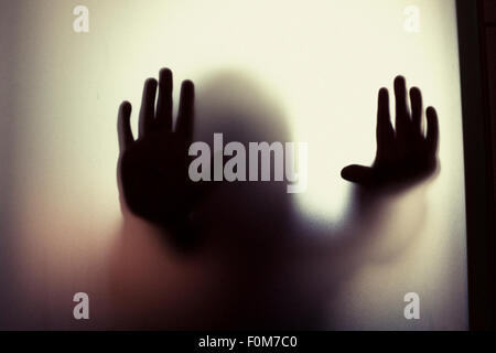 Silhouette of little child holding out hands. Conceptual image of childhood fears, abuse and safety of children. Stock Photo