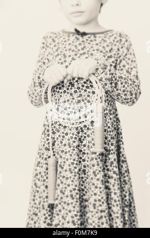 Portrait of little girl in dress with flowers. She is holding a jump rope in her hands. Stock Photo