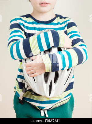 Little girl holding a bicycle helmet in her arms. Conceptual image of safety and protection for children learning to ride a bike Stock Photo