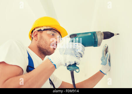 builder in hardhat working with drill indoors Stock Photo