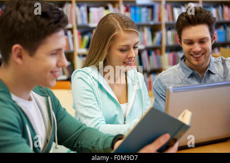 happy students with laptop and book at library Stock Photo