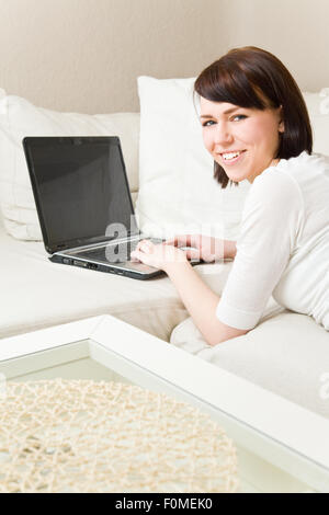 Young woman working on a laptop on a sofa Stock Photo