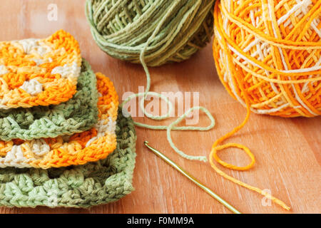 Handmade colorful crochet granny afghan square with skein on wooden table. Selective focus Stock Photo