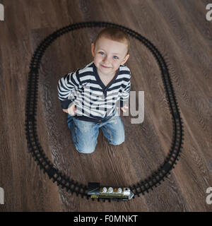 little boy builds toy railroad Stock Photo